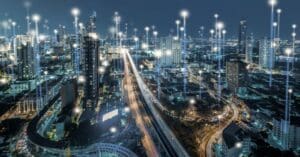 A city scape at night with points of vertical light beams scattered throughout it.