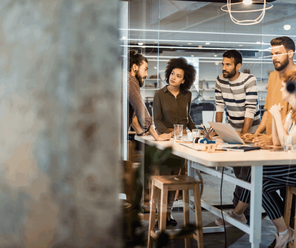 A group of diverse people working around a table, discussing work.