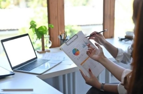 Two professionals holding a clipboard with a paper containing data on it.