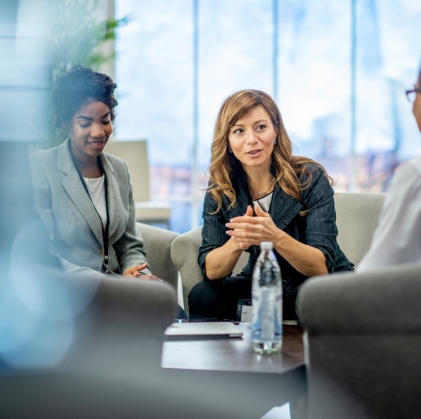 A business woman sitting among other business people in soft chairs discussing.