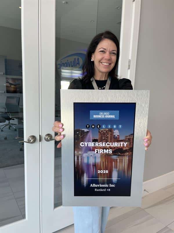 Elizabeth Huy standing indoors and smiling while holding a framed Orlando Business Journal award plaque for The List: Cybersecurity Firms 2025, showing Alluvionic ranked No. 8.