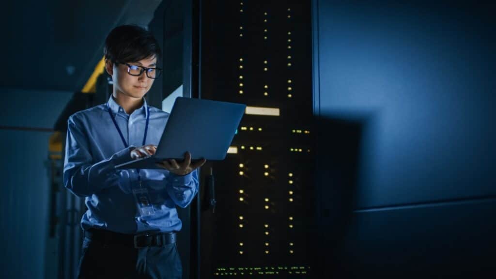IT professional using a laptop in a server room