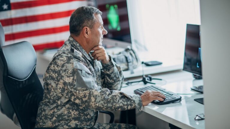 Military service member working at a computer workstation during defense operations